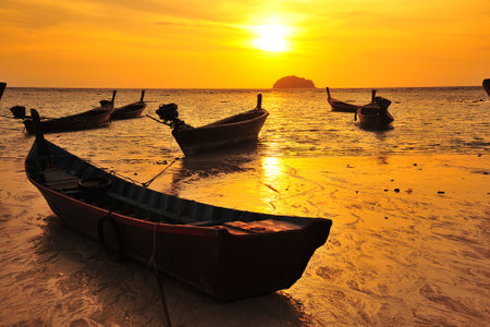 Fishing boats on the beach at sunset, Krabi, Thailandの写真素材