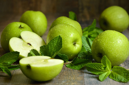 Green apples with mint leaves on wooden table.の写真素材