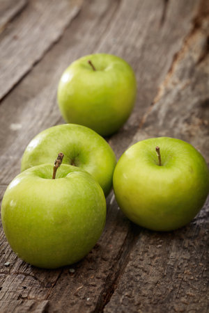 Green apples, on wooden surface.の写真素材
