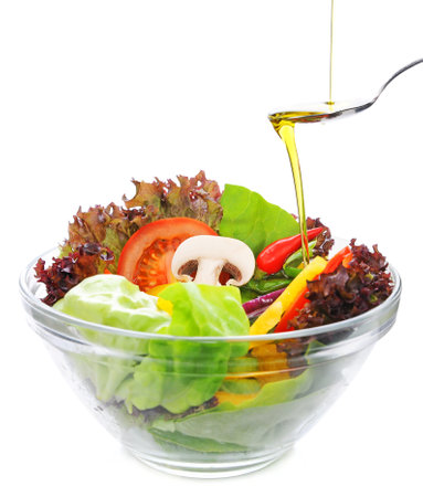 Fresh vegetable salad in glass bowl with oil isolated on white background.の写真素材