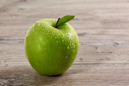 Fresh green apple with water drops on wooden table, close-upの写真素材