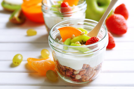 Yogurt with fresh fruits on white wooden table, closeupの写真素材