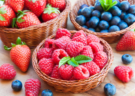 Strawberries, blueberries and raspberries in a basketの写真素材