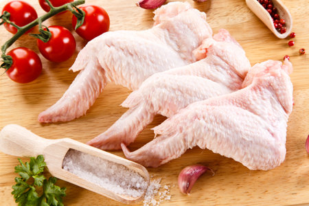 Raw chicken wings with spices on wooden cutting board. Selective focus.の写真素材