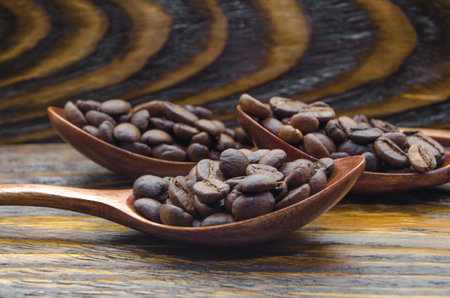 Coffee beans in wooden spoon on wooden background. Close up.の写真素材