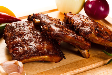 grilled ribs on a wooden board with vegetables on a white backgroundの写真素材