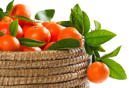 Ripe tangerines with leaves in a basket on a white backgroundの写真素材