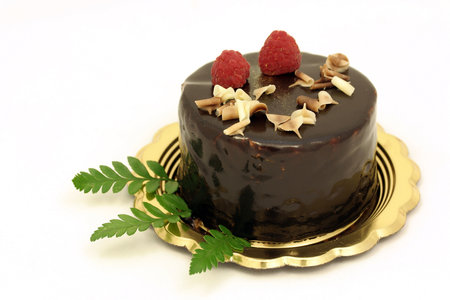 Chocolate cake with raspberries and nuts on a golden plateの写真素材