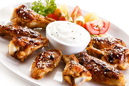 Grilled Chicken Wings with Sauce and Vegetables on White Plate.の写真素材