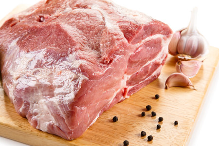 Raw pork meat on cutting board with garlic and pepper on white backgroundの写真素材