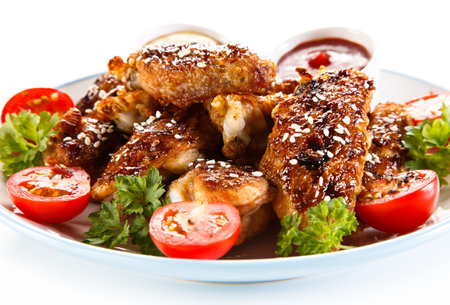Grilled Chicken Wings with Sesame Seeds and Cherry Tomatoes on White Backgroundの写真素材