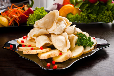 Boiled dumplings served on a plate with slices of potatoesの写真素材