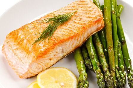 Baked salmon with asparagus and lemon on a white plateの写真素材