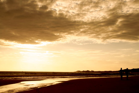 Silhouette of a man standing on the beach at sunset.のeditorial素材