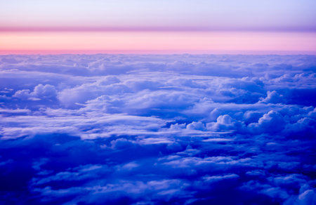 Clouds at sunset as seen through window of an aircraft flying above the clouds