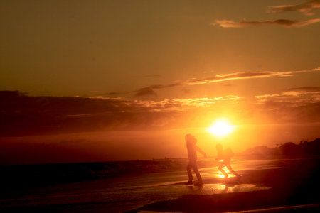 Silhouette of a mother and son on the beach at sunsetのeditorial素材