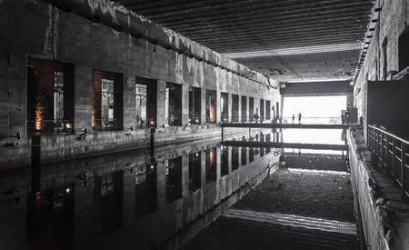 The interior of an old factory building with reflections in the water.のeditorial素材