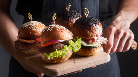 Hamburgers on a wooden board in the hands of a chefのeditorial素材