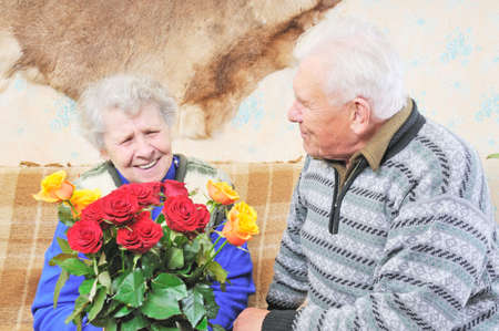 old woman with roses and old man sit near herの写真素材