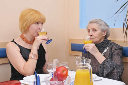 two happy womans drinking wine and juiceの写真素材