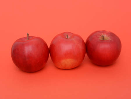 three red apples on the red backgroundの写真素材