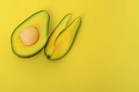 Half avocado and some slice on a yellow background. Top viewの写真素材