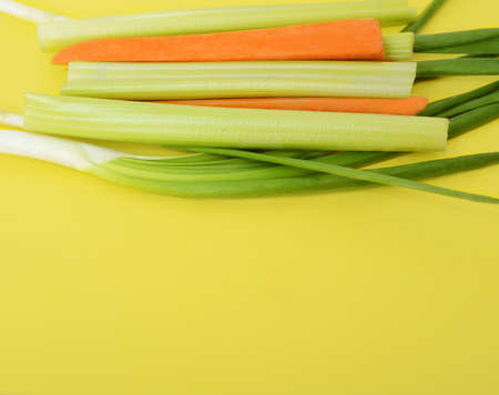 Fresh green celery, onion and carrots on yellow backgroundの写真素材