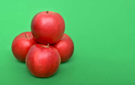 Four ripe red apples on green background. Red apple pyramidの写真素材