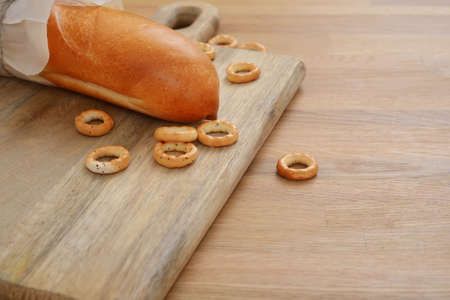 French bread and bagels on cutting board on wooden tableの写真素材