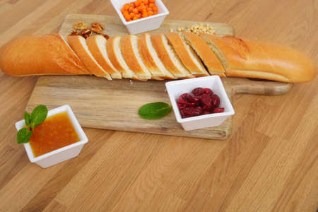 Side view of sliced french bread and three bowl of jamの写真素材