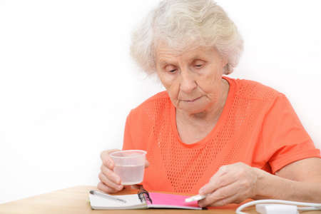 Senior woman with pills and glass of water at home. Healthy strong medical conceptの写真素材