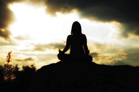 Woman training yoga and meditation on the rock at the mountainの写真素材