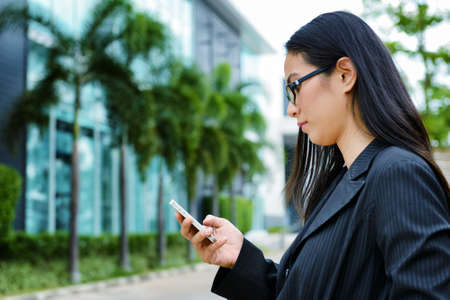 Asian business woman using mobile phone at outdoorの写真素材