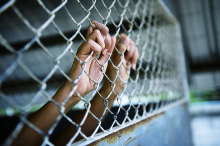Hands of the prisoner in jail (image toned)の写真素材