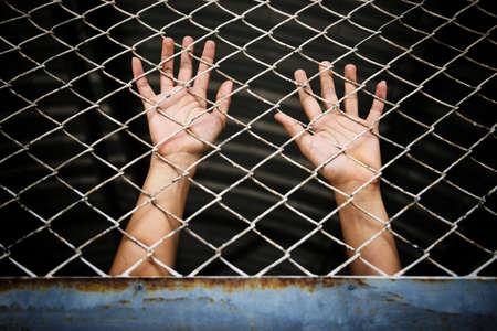 Hands of the prisoner in jail (image toned)の写真素材