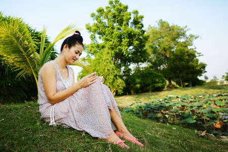 Woman reading book under a tree at public parkの写真素材