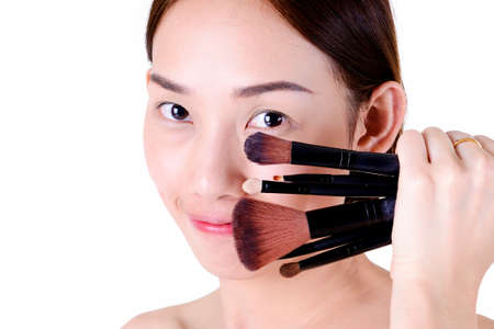 Beautiful asian woman with makeup brushes isolated on white backgroundの写真素材
