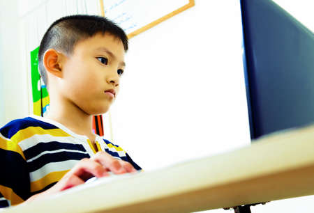 Asian little boy using laptop for knowledgeの写真素材