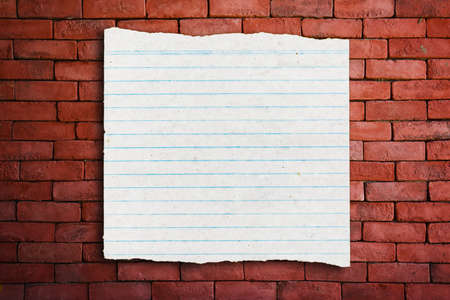 Vintage grungy lined paper on red brick wall