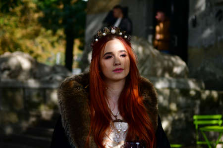 sexy, long-haired, young girl on the cobblestones in front of a stone fortress and metal iron door...