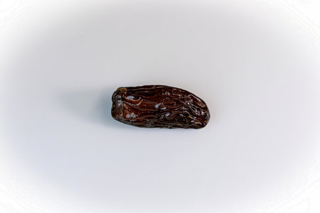 date. one date. dried dates close-up on a white background. sweet fragrant delicious brown shiny dateの写真素材