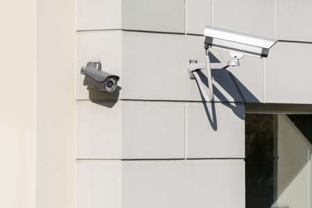 CCTV cameras on modern white building wall in cityの写真素材
