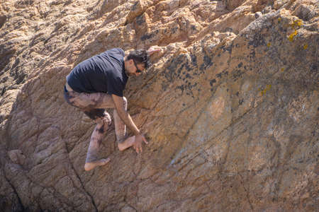 Brave man without insurance climbing cliff, copy space, Spain
