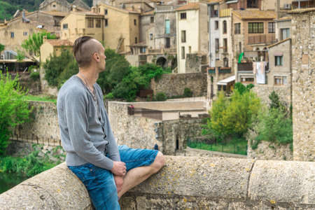 Man looking at traditional European cityscape - ancient houses of Middle Ages in Besalu, Girona,...