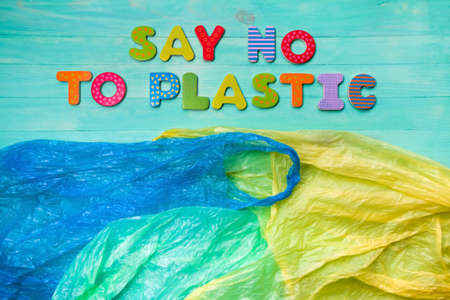 Plastic bags and inscription of colorful wooden letters: say no to plastic. Flat lay, wooden turquoise background. Ban plastic conceptの写真素材