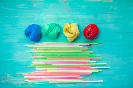 Colorful plastic bags and straws on wooden turquoise background. Flat lay. Ban plastic conceptの写真素材