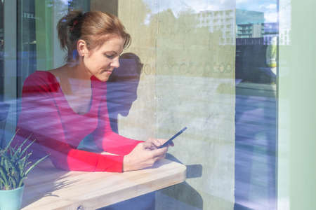 Beautiful woman in red using smartphone for business, online shopping, transfer money, financial,...