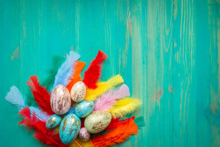 Easter eggs and feathers on vintage wooden turquoise painted table. Modern Easter decoration....