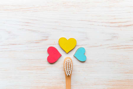 One wooden bamboo toothbrush with wooden hearts on white wood background and copy spaceの写真素材
