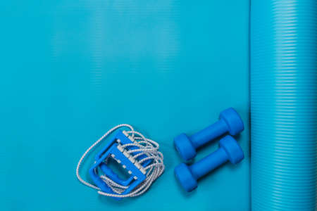 Blue dumbbells and chesty expander on yoga mat. Fitness concept